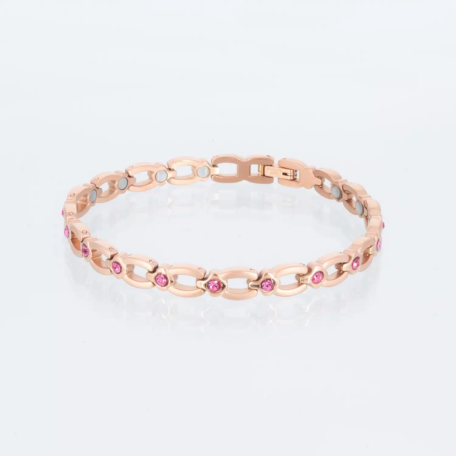 Ein rosegoldenes Magnetarmband, matt gebürstet, mit glänzenden Zwischenteilen, die jeweils einen pinkfarbenen Zirkoniastein enthalten