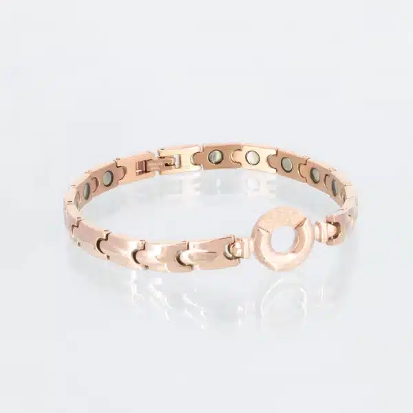 Ein rosegoldenens Magnetarmband mit dekorativen Tropfen auf den einzelnen Gliedern. Ein Teil des Kreises in der Mitte ist mit Zirkoniasplittern bedeckt