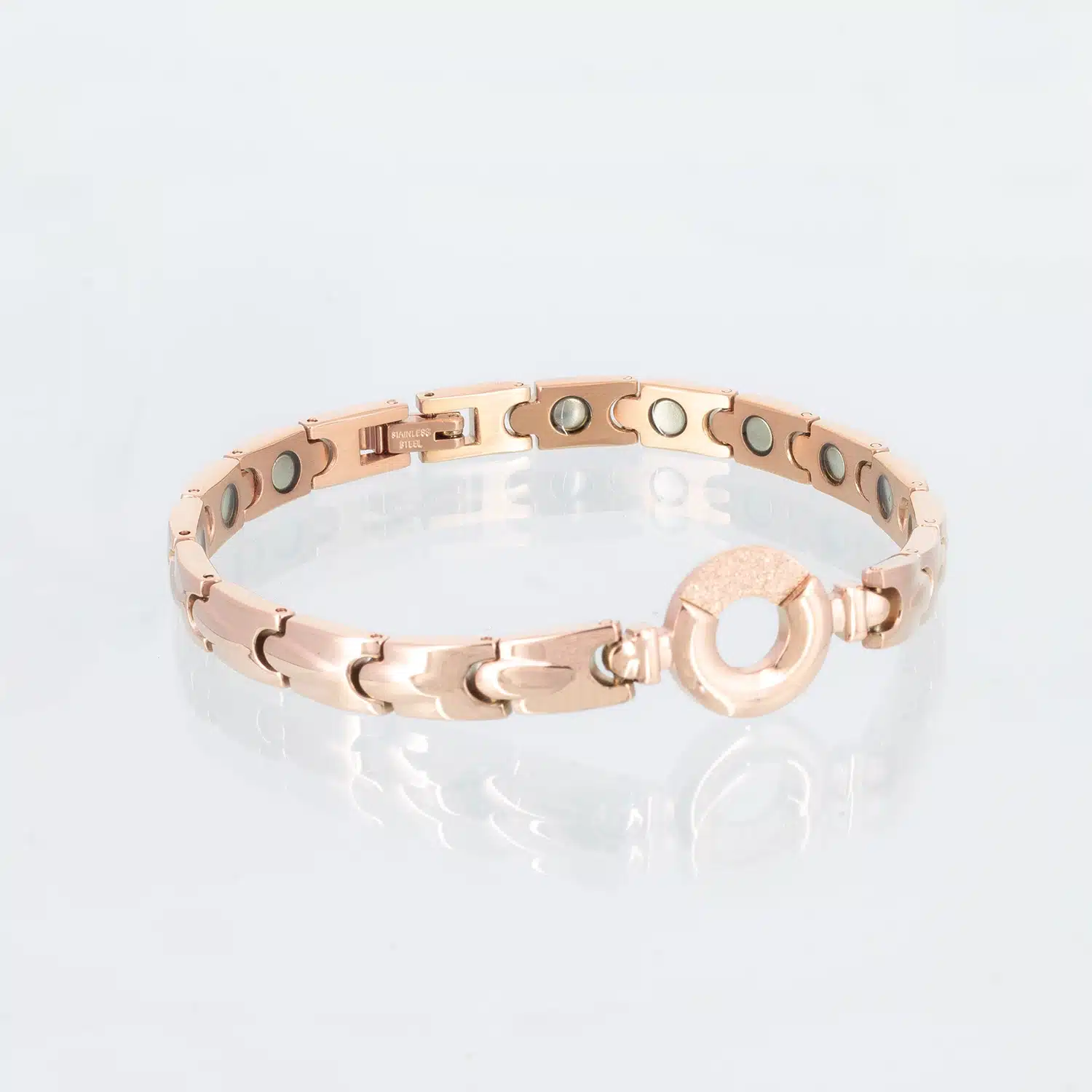 Ein rosegoldenens Magnetarmband mit dekorativen Tropfen auf den einzelnen Gliedern. Ein Teil des Kreises in der Mitte ist mit Zirkoniasplittern bedeckt