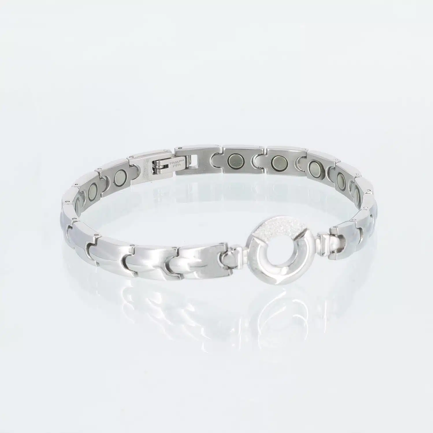 Ein silbernes Magnetarmband mit dekorativen Tropfen auf den einzelnen Gliedern. Ein Teil des Kreises in der Mitte ist mit Zirkoniasplittern bedeckt