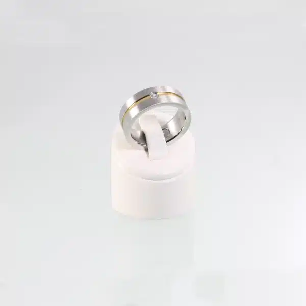 Ein silberner Magnetring mit einem goldenen Streifen in der Mitte. Auf der Oberfläche enthält er einen eingelassenen Zirkoniastein