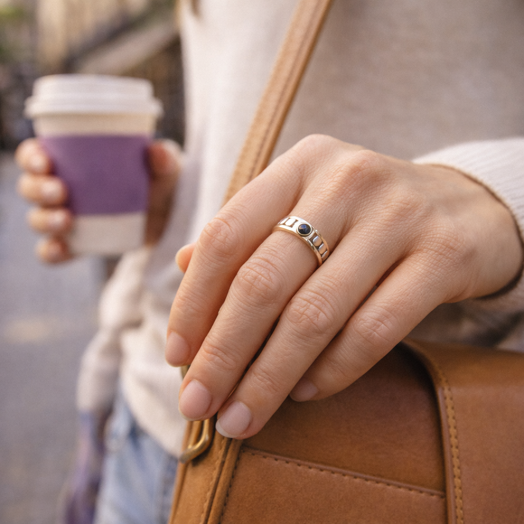 Hand trägt einen silbernen Magnetring am Finger und hält eine Tasche