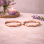 Zwei roségoldene Magnetarmbänder liegen nebeneinander auf einer hellen Oberfläche