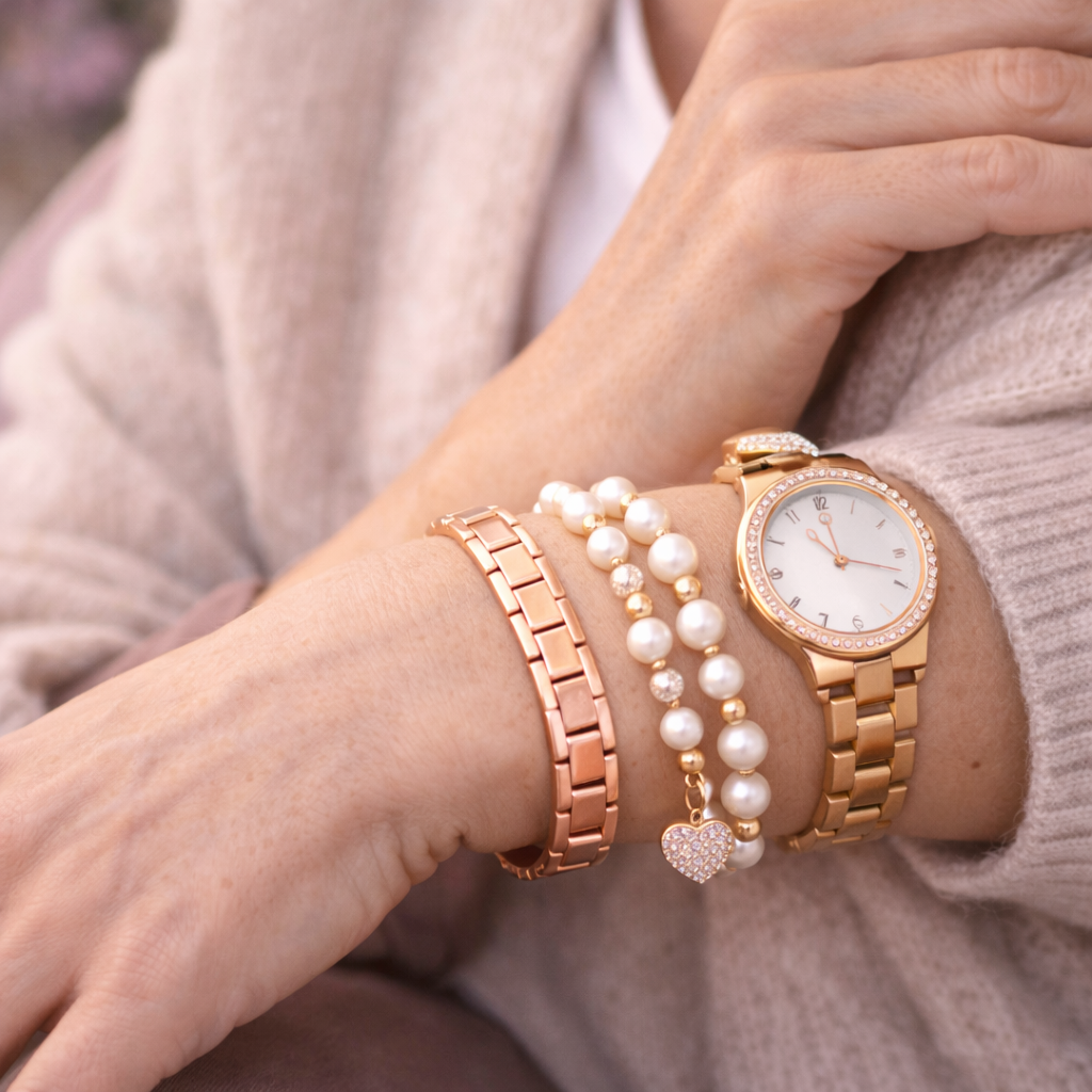 Roségoldenes Magnetarmband wird zusammen mit einer Armbanduhr und weiteren Armbändern am Handgelenk getragen