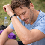 Sportlicher Mann trägt schwarzes Magnetarmband nach dem Training im Freien